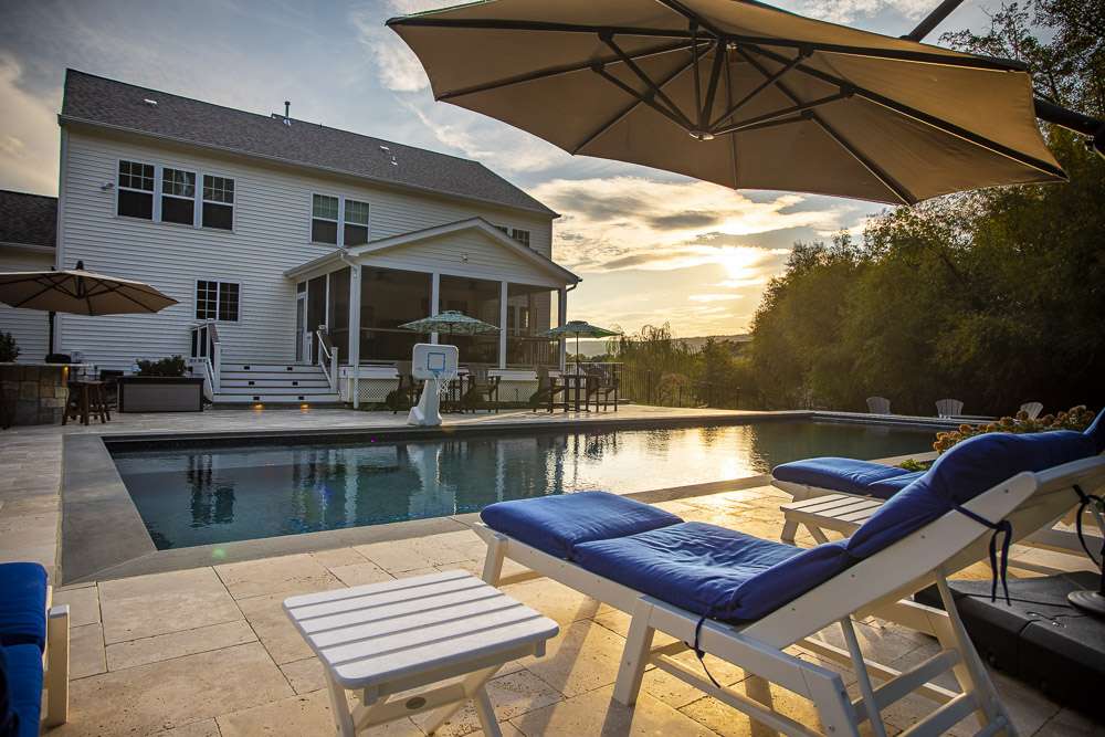 pool with basketball hoop and lounge chairs